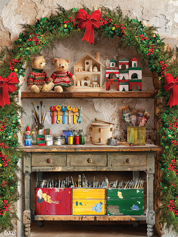 Santa's Workshop Photography Backdrop - Santa's Workshop photography backdrop featuring a rustic workbench with paint pots, brushes, wooden toys, and teddy bears, framed by a garland arch with red bows.