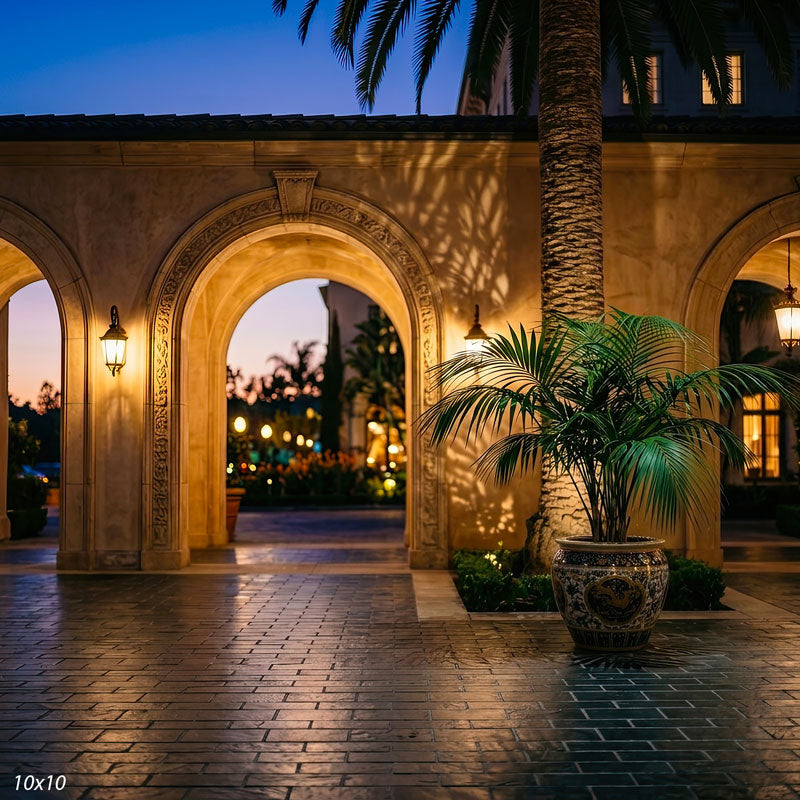 Wider view of the stucco courtyard archway, showing more of the glazed urn and bokeh garden, a scenic photography backdrop.