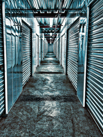 Sleek Industrial Storage Corridor Photography Backdrop - A long corridor in a modern storage facility with metallic roll-up doors and a polished concrete floor, creating a sleek industrial atmosphere.