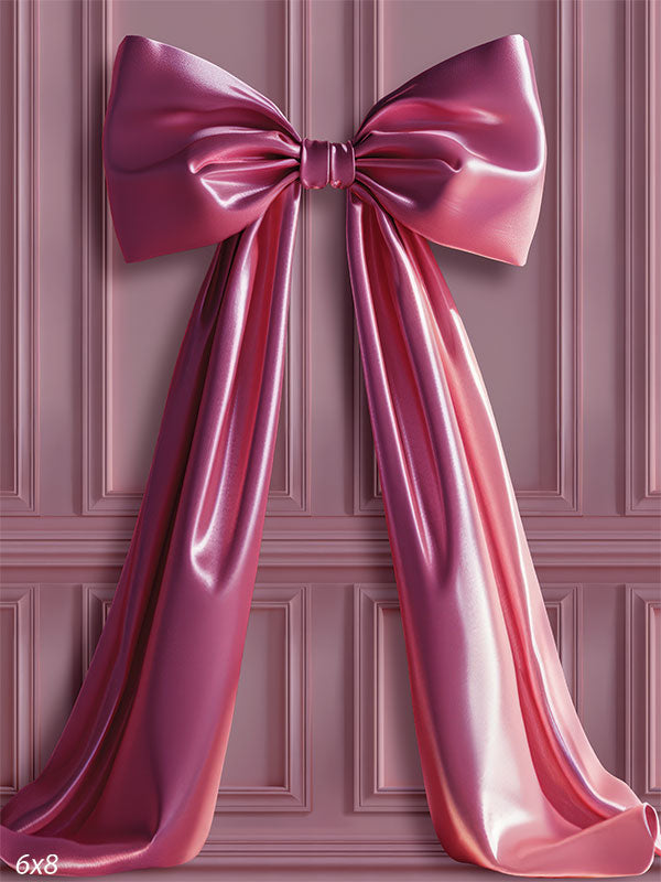 Soft pink paneled wall backdrop featuring a draped satin magenta bow.
