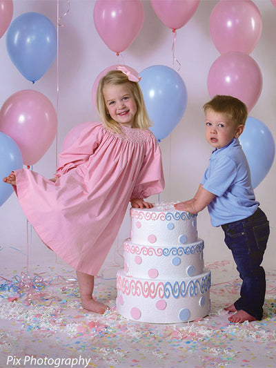 Light gray seamless backdrop supports a calm birthday studio setting with boy and prop cake.