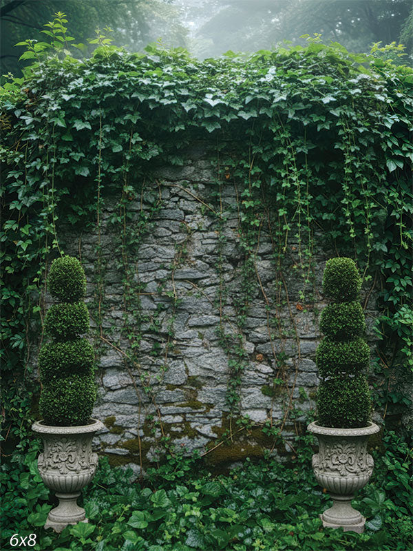 Printed photography backdrop showing a stone garden wall with hanging ivy, ground greenery, and two topiary urns near the lower corners. Soft fog and treetops sit above the wall line.