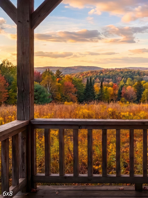 Autumn valley photography backdrop looking from a rustic porch railing over rolling gold and amber foliage under a warm sunset sky.