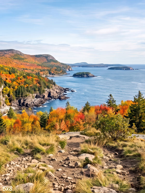 Autumn coastline photography backdrop with rocky cliffs of orange and evergreen foliage dropping to a deep blue ocean cove seen from a rocky overlook.