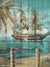 Tropical Sailing Ship and Palm Tree Wooden Mural Backdrop - A detailed mural painted on a wooden surface, depicting a grand sailing ship with red "X" marked sails navigating calm blue waters, a swaying palm tree, and wooden posts with ropes in the foreground, evoking a nautical and tropical atmosphere.