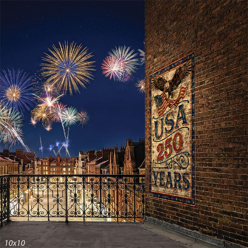Printed photography backdrop featuring a rooftop city scene with a brick wall mural reading USA 250, an ornate railing, and fireworks overhead. The studio background includes illuminated buildings beneath a dark evening sky.
