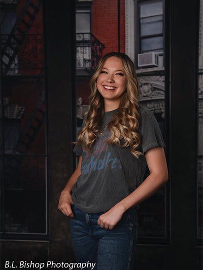 Loft-style portrait backdrop with red brick texture and tall city windows—ideal for editorial senior sessions.