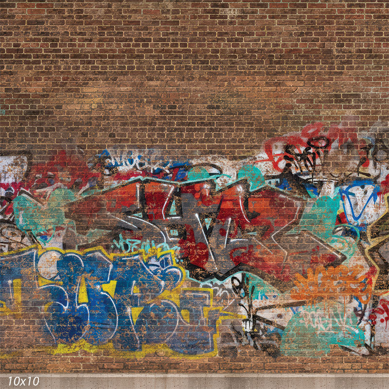 Printed studio background featuring a weathered brick wall with multicolor graffiti paint layers and faded spray outlines across the lower half. The brick pattern continues above the graffiti behind a subject.