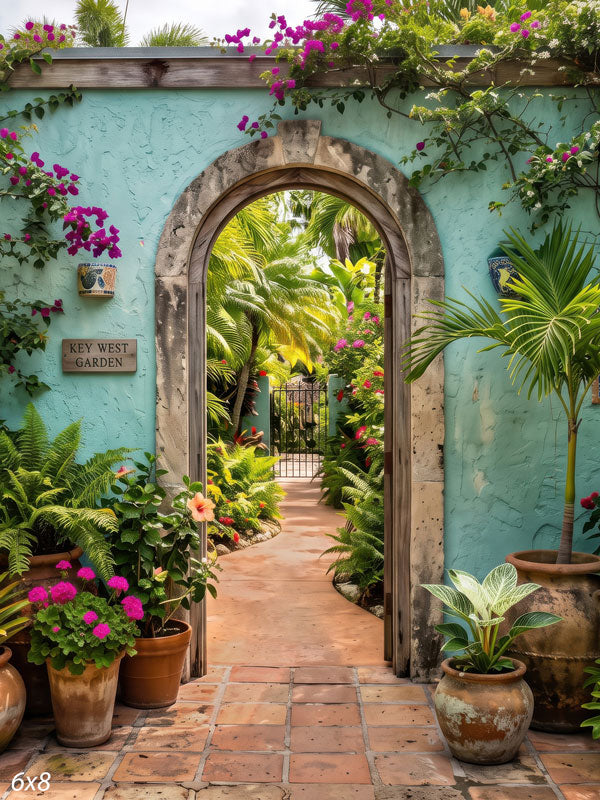 Turquoise stucco archway opening onto a tropical courtyard with magenta bougainvillea, palms and terracotta pots along a tiled path, a scenic photography backdrop.