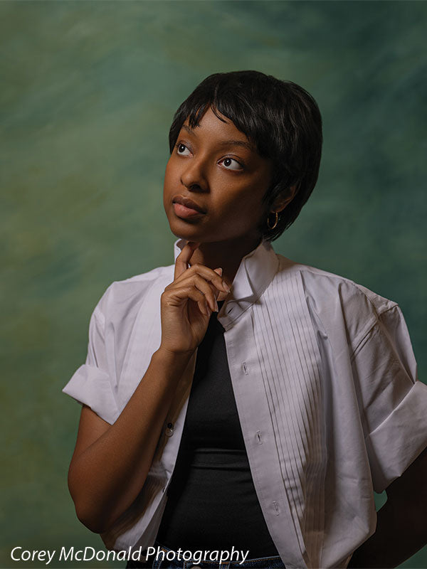 Green abstract hand-painted photography backdrop shown in a studio senior portrait with a young woman holding a hand to her chin, gazing up OM-2644