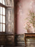 Vintage Pink Wall and Floral Backdrop - Photography backdrop featuring a distressed pink wall with an antique finish and a wooden table adorned with delicate floral arrangements.