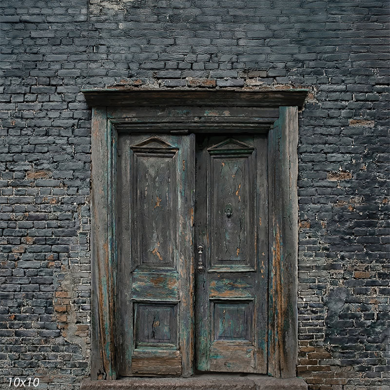 This studio background features distressed wooden double doors framed by aged brickwork with cool gray tones and heavy surface texture for portrait photography.