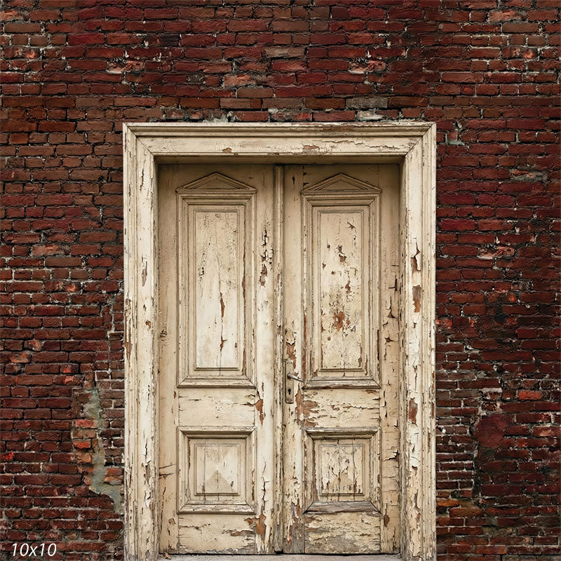 This studio background features aged wooden double doors with chipped cream paint framed by deep red brick masonry, forming a rustic architectural portrait backdrop.