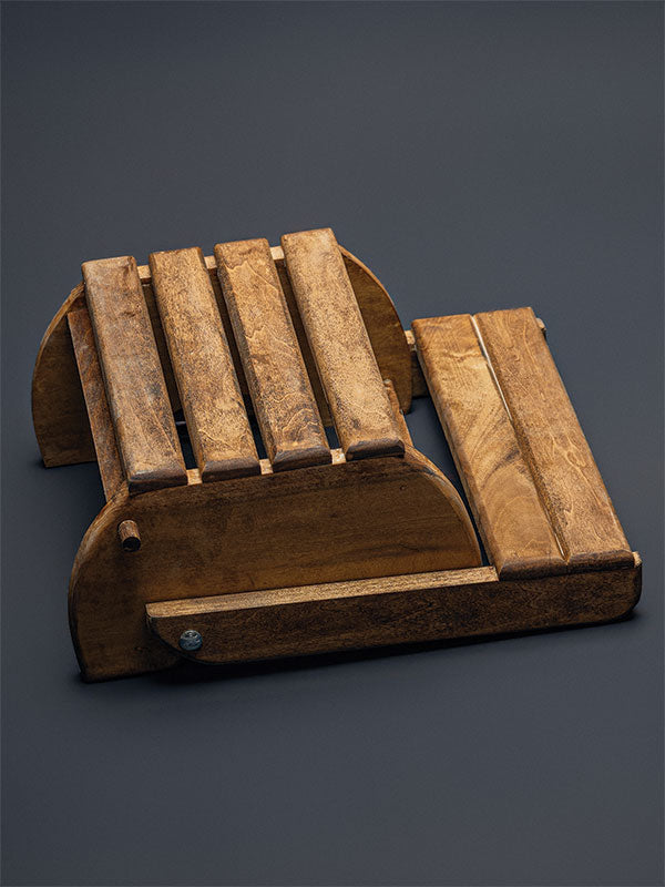 Wooden step stool bench photography prop with a slatted seat and curved sides, shown in an angled view folded flat as a step stool on a plain grey studio background.