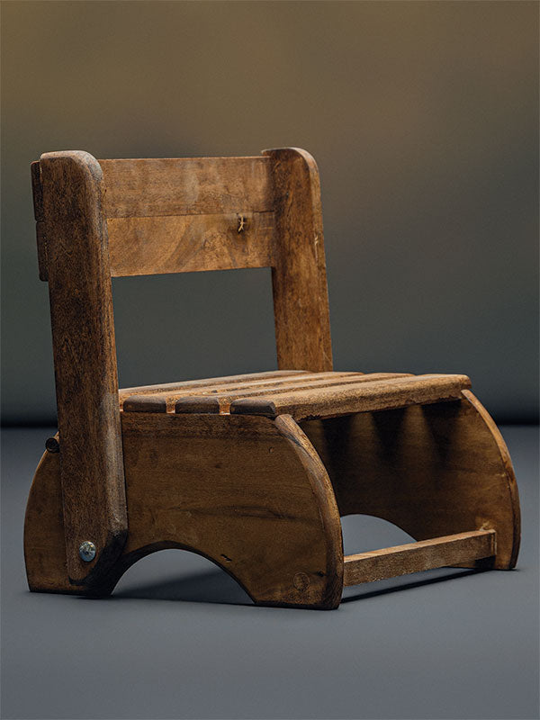 Wooden step stool bench photography prop with a slatted seat and curved sides, shown in a front-angle view with the backrest raised on a plain grey studio background.