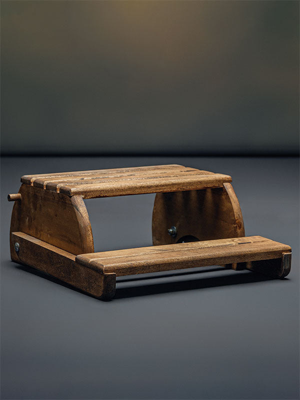 Wooden step stool bench photography prop with a slatted seat and curved sides, shown in a low side view folded flat as a step stool on a plain grey studio background.