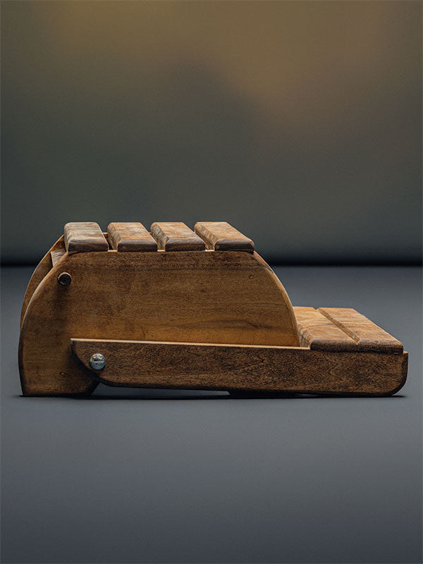 Wooden step stool bench photography prop with a slatted seat and curved sides, shown in a side view folded flat with the arched end panels on a plain grey studio background.