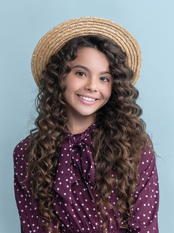 Close-up portrait of a young girl against a light blue seamless photography backdrop paper for studio portraits.