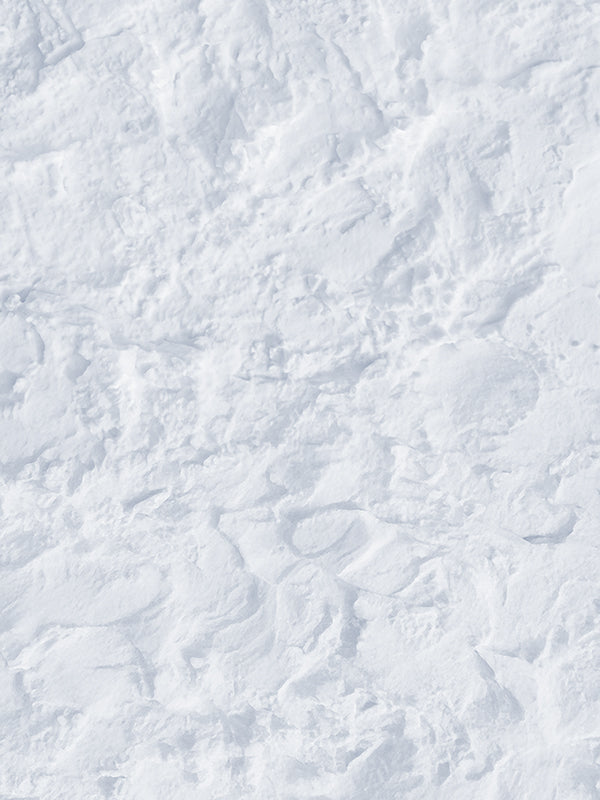 Bright white packed snow surface with uneven drifts, shallow ridges, and soft blue-gray shadows, a winter photography floor drop.