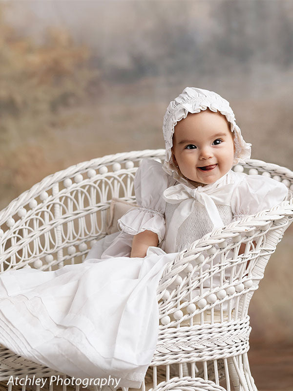 Ansel soft misty meadow with trees photography backdrop shown with a baby in a lace bonnet smiling on a white wicker settee, close portrait CP-8845