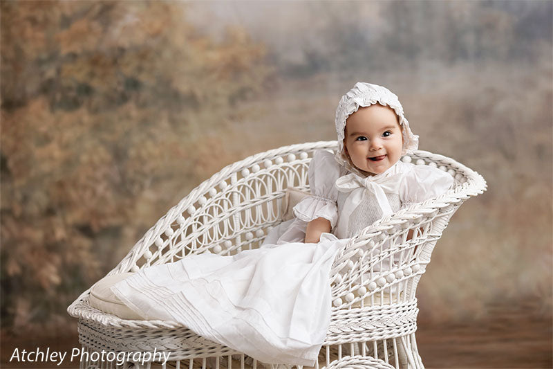 Ansel soft misty meadow with trees photography backdrop shown with a baby in a white heirloom gown on a white wicker settee, wide view CP-8845