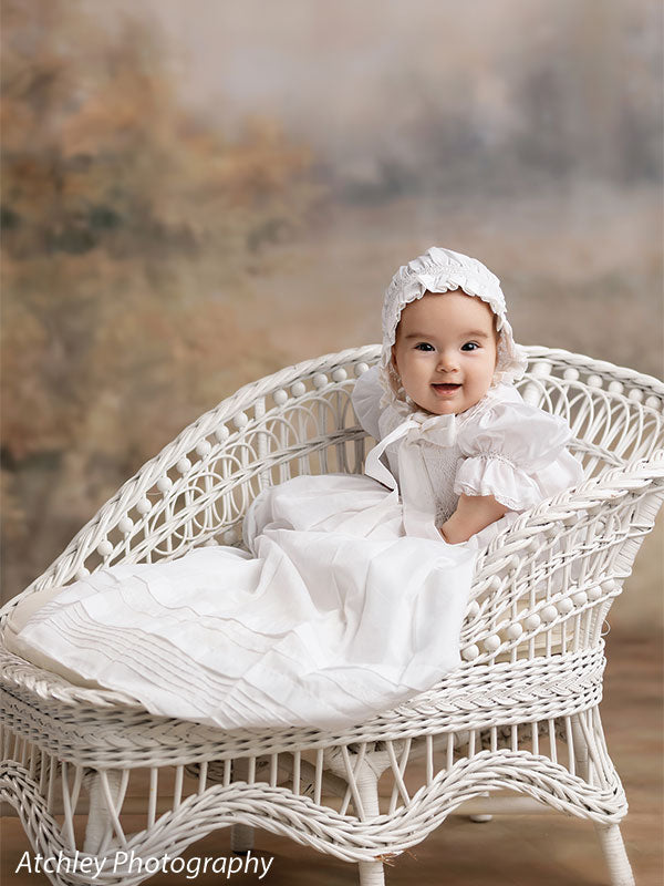 Ansel soft misty meadow with trees photography backdrop shown with a baby in a white heirloom gown seated on a white wicker settee CP-8845