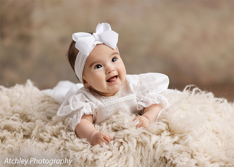 Ansel soft misty meadow with trees photography backdrop shown with a baby with a white bow headband on a cream fur rug, wide view CP-8845