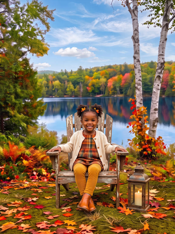 Autumn lake birch reflection photography backdrop shown in a fall studio portrait with a young girl in a plaid dress seated in a wooden Adirondack chair by a lantern CP-9037