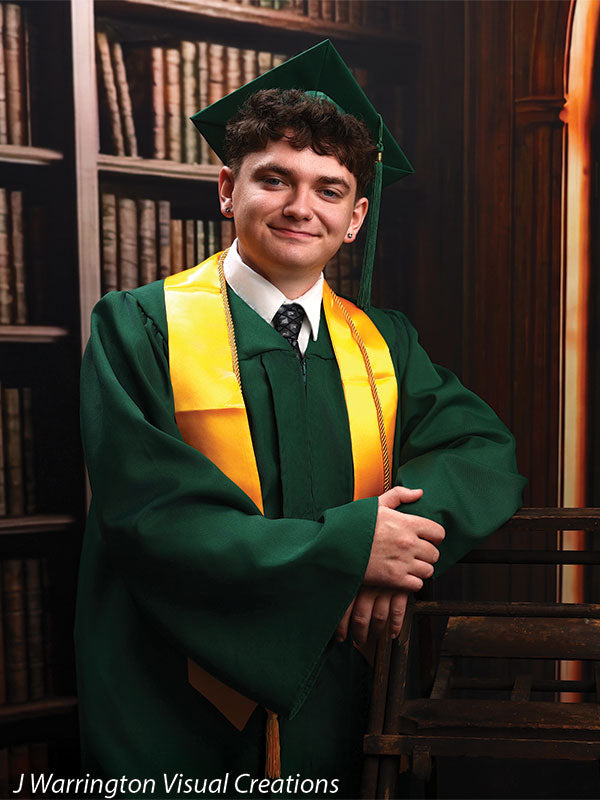 Benedict dark wood library bookcase photography backdrop shown with a senior in a green cap and gown with arms crossed, leaning on a library ladder CP-8839