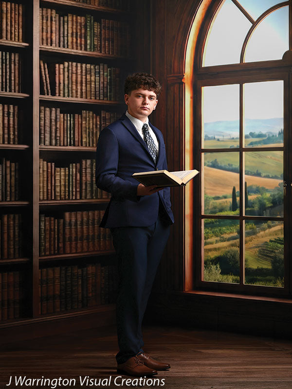 Benedict dark wood library bookcase photography backdrop shown with a senior in a navy suit holding an open book, full-length by the arched window CP-8839
