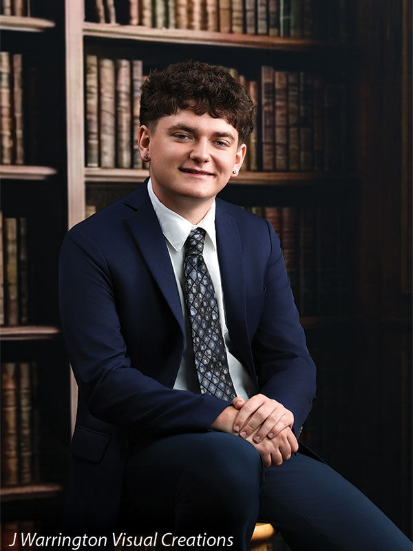 Benedict dark wood library bookcase photography backdrop shown with a senior in a navy suit seated with hands clasped, smiling CP-8839