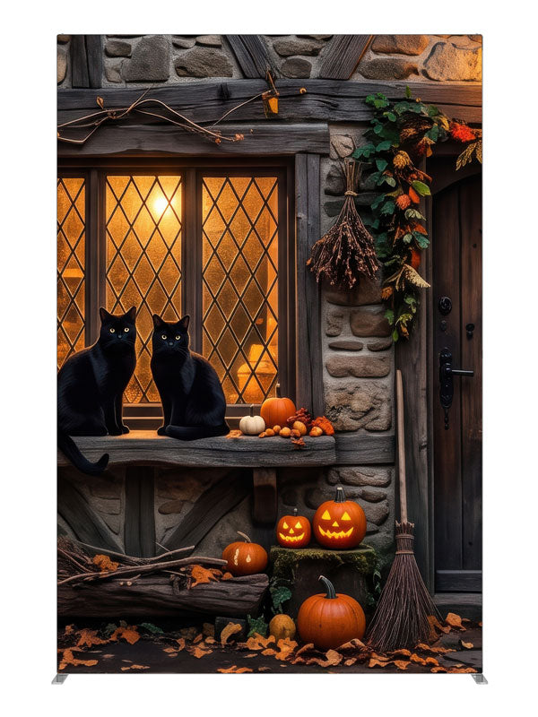 Two black cats on a glowing leaded cottage window in a stone-and-timber wall with jack-o'-lanterns, 5ft photography backdrop panel for Denny StudioEdge silicone edge frame