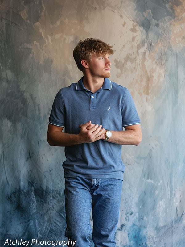 Senior portrait backdrop featuring a modern blue abstract texture with a young man in casual attire, ideal for contemporary male studio sessions.