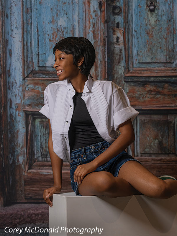 Blue Desire Street, photography backdrop panel for Denny StudioEdge silicone edge frame, shown with a senior girl seated on a white posing cube with legs crossed, smiling SECP-7654