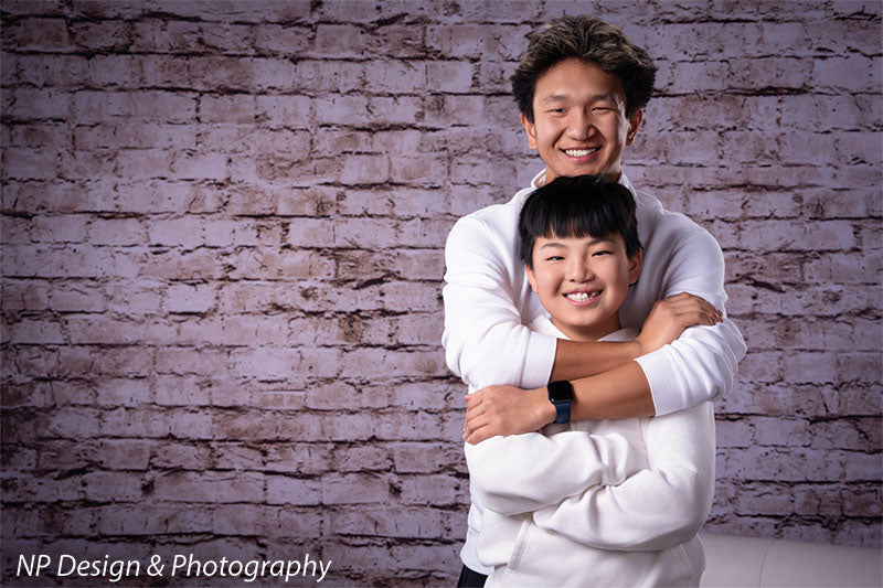 Broadway Brick exposed brick photography backdrop shown with two brothers hugging by the brick wall, wide view CP-7742