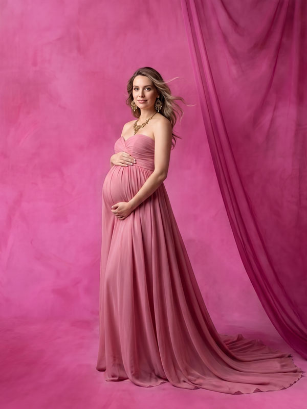 Bubblegum vivid pink mottled texture photography backdrop, shown with an expectant mother in a flowing pink gown with a hand on her belly CP-9008
