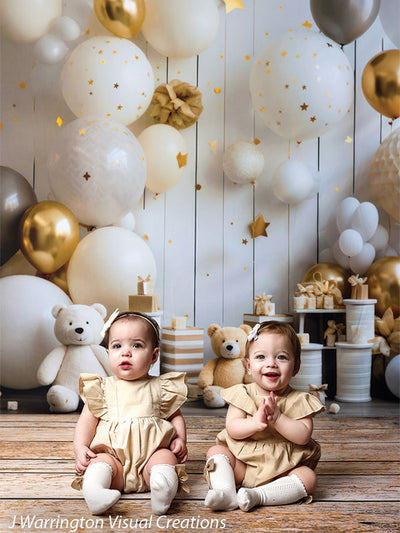Smiling twin toddlers in matching beige outfits posing with gold stars and teddy bears in a whimsical Bears and Stars Cake Smash Backdrop birthday scene.