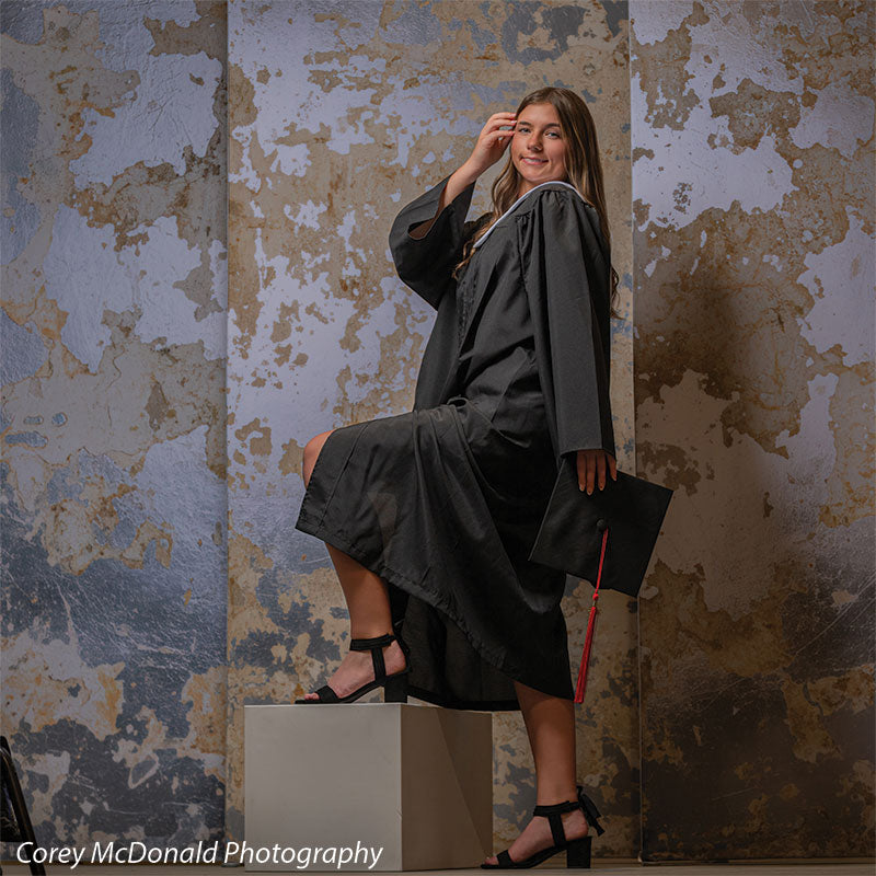 Caspian Silver and Beige Weathered Texture, photography backdrop panel for Denny StudioEdge silicone edge frame, shown with a senior girl in a graduation gown holding her cap with a foot on a white posing cube SECP-8856
