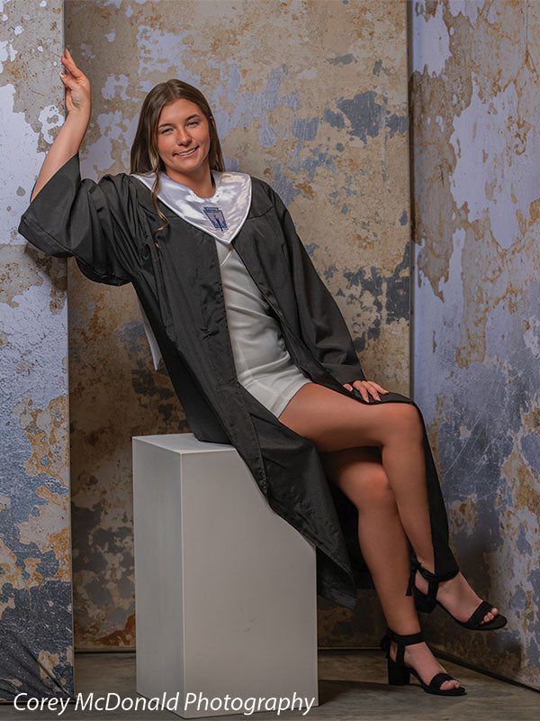 Caspian Silver and Beige Weathered Texture, photography backdrop panel for Denny StudioEdge silicone edge frame, shown with a senior girl in a graduation gown seated on a white posing cube with legs crossed SECP-8856