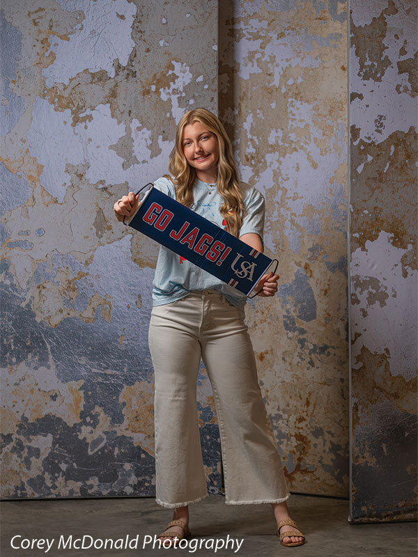 Caspian Silver and Beige Weathered Texture, photography backdrop panel for Denny StudioEdge silicone edge frame, shown with a senior girl standing full-length holding a Go Jags banner SECP-8856