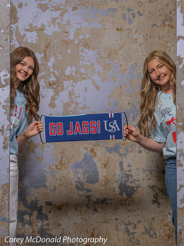Caspian Silver and Beige Weathered Texture, photography backdrop panel for Denny StudioEdge silicone edge frame, shown with two senior girls holding a Go Jags USA banner in a close view SECP-8856