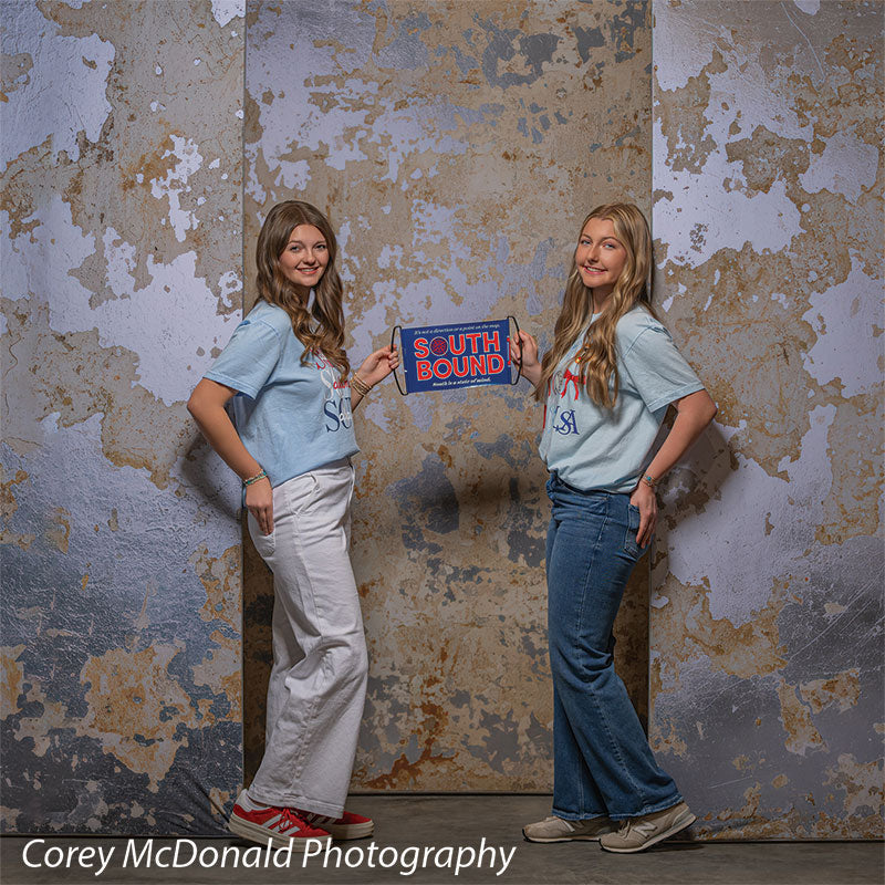 Caspian Silver and Beige Weathered Texture, photography backdrop panel for Denny StudioEdge silicone edge frame, shown with two senior girls holding a South Bound banner between them SECP-8856
