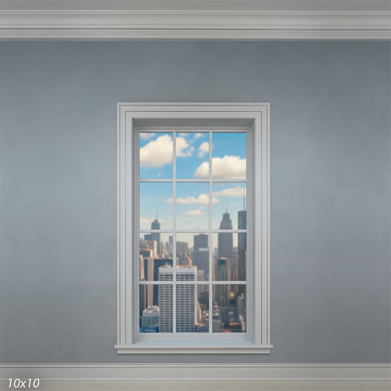 Wider studio scene with a centered white window on a gray wall, revealing more negative space around the frame and a distant urban skyline under a clear, cloud-dotted sky.