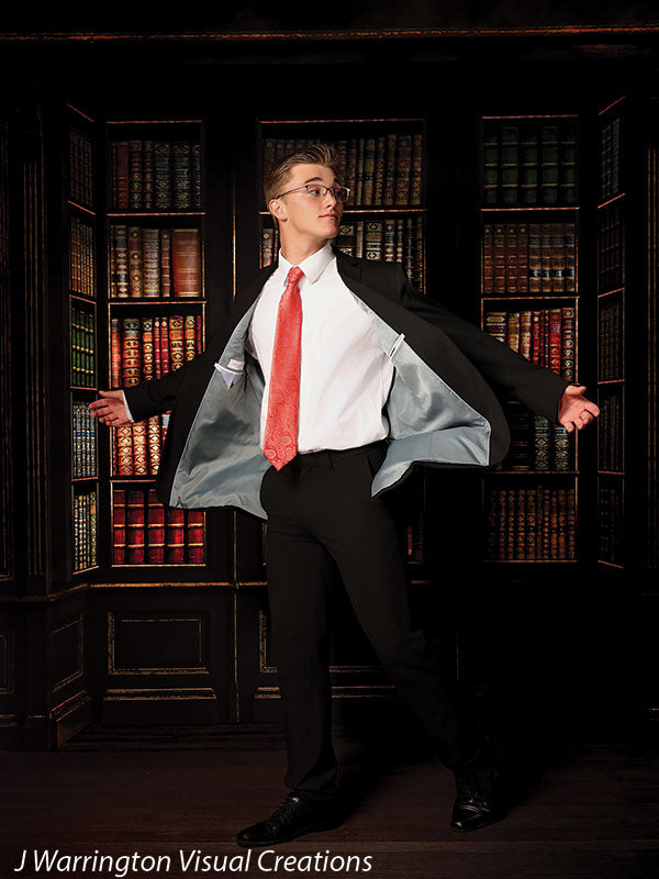 Senior boy standing confidently with suit jacket open on a classic hardwood floordrop, perfect for bold senior portraits in studio settings.