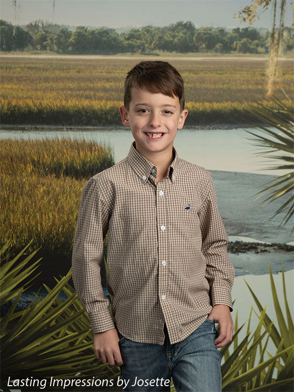 Coastal Marsh View photography backdrop showing golden marsh grass and a tidal creek with a distant treeline and palmetto fronds, shown with a young boy in a tan plaid button-down standing and smiling CP-8486