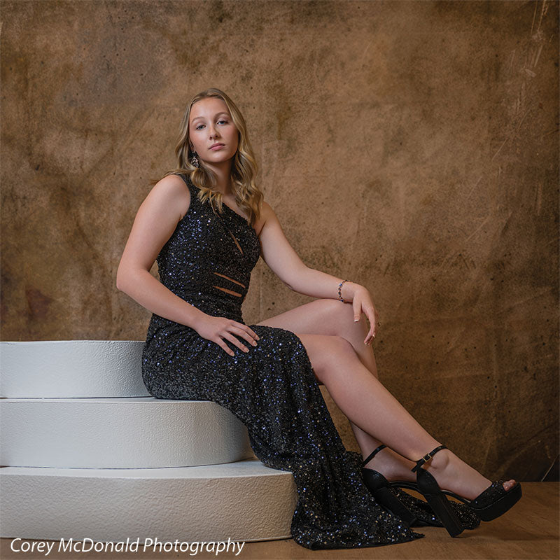 Corner Steps posing prop shown with a senior girl in a black sequin gown seated on the white foam corner steps with legs crossed Cor-Step