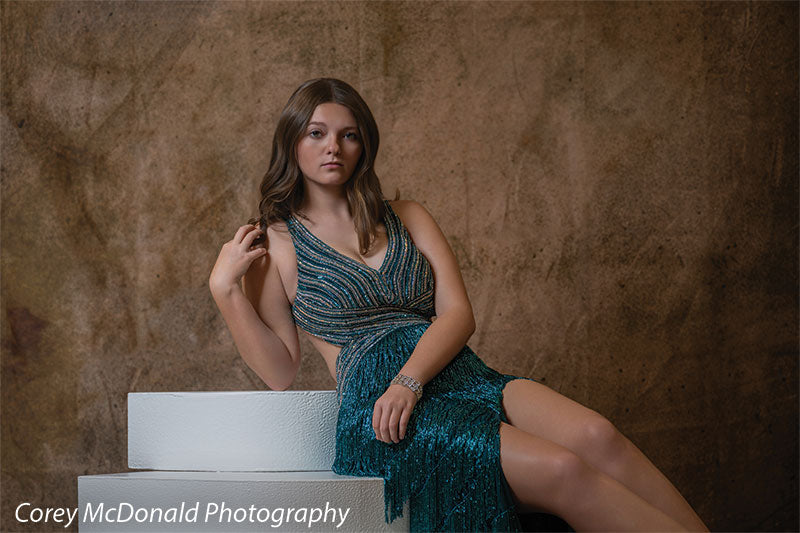 Corner Steps posing prop shown with a senior girl in a teal fringe gown seated on the white foam corner steps with a hand in her hair Cor-Step