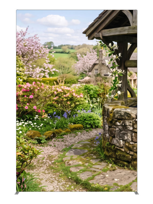 A spring cottage garden with a stone wishing well, a flowering path and a cottage with green hills, 5ft photography backdrop panel for Denny StudioEdge silicone edge frame