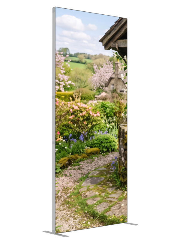 A spring cottage garden with a stone wishing well, a flowering path and a cottage with green hills, 3ft photography backdrop panel for Denny StudioEdge silicone edge frame, angled view