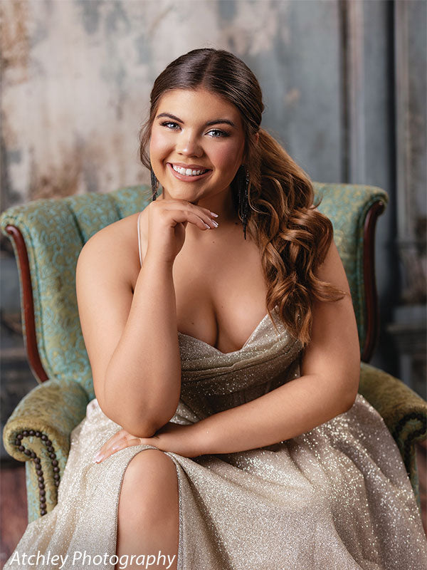 Luxurious vintage French panel backdrop with an ornate blue-green armchair, highlighting a female senior model in a shimmering gold dress, ideal for glamour or senior sessions.